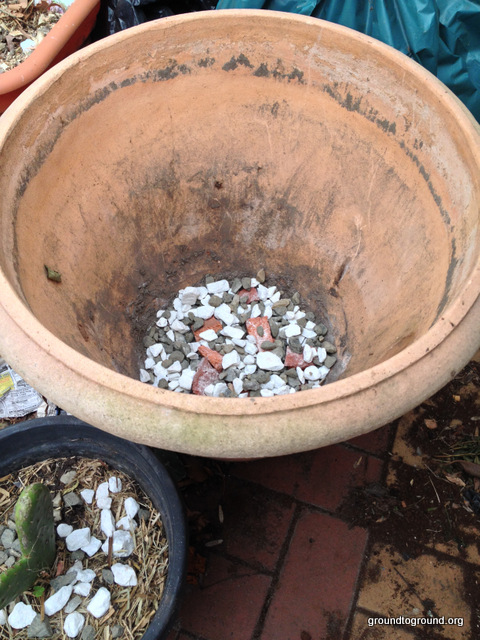 Rocks placed at the base of a garden pot for drainage